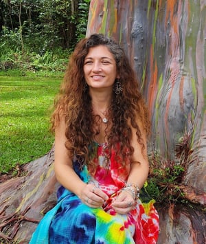 Juliana Hamon sitting in front of a rainbow eucalyptus tree