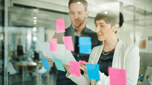 marketers in front of a glass wall covered in post-it notes