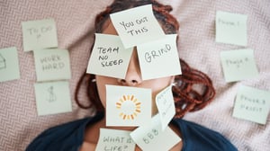 Woman laying down with face covered in post-it notes with words of encouragement from Catalyst