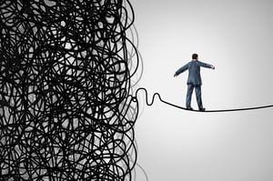 business man balancing on a wire tied in knots